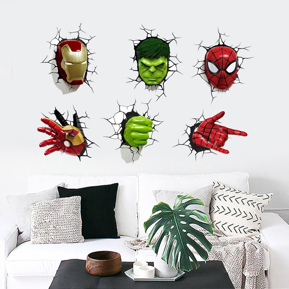 Six 3D wall decals of Marvel superheroes (Iron Man, Hulk, Spider-Man, and their fists/eyes) applied to a white wall above a modern white sofa with decorative pillows.