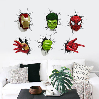 Six 3D wall decals of Marvel superheroes (Iron Man, Hulk, Spider-Man, and their fists/eyes) applied to a white wall above a modern white sofa with decorative pillows.