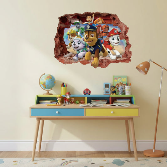 A children's room scene with a colorful Paw Patrol wall decal showing the characters bursting through a torn wall above a small desk. The room includes a desk with blue and yellow drawers, toys, a globe, a floor lamp, and a light-colored wall.